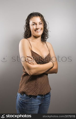 Portrait of pretty young adult Caucasian brunette female with arms crossed smiling and looking at viewer.