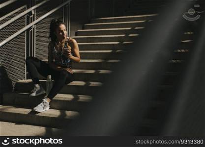 Portrait of pretty young female runner resting on stairs