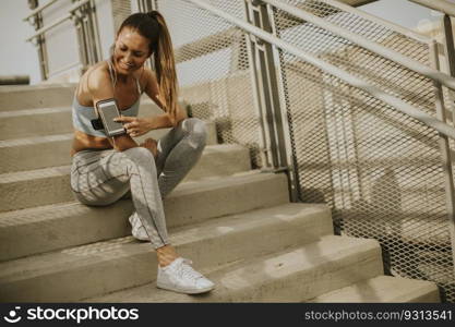 Portrait of pretty young female runner resting on the stairs