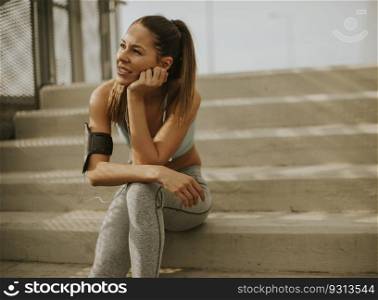 Portrait of pretty young female runner resting on the stairs