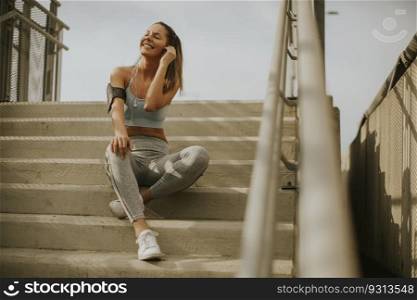 Portrait of pretty young female runner resting on the stairs