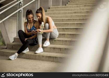 Portrait of pretty young females runner resting on stairs