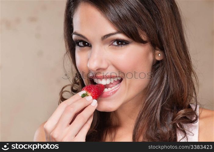 Portrait of pretty young woman eating a strawberry