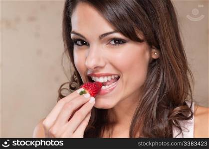 Portrait of pretty young woman eating a strawberry