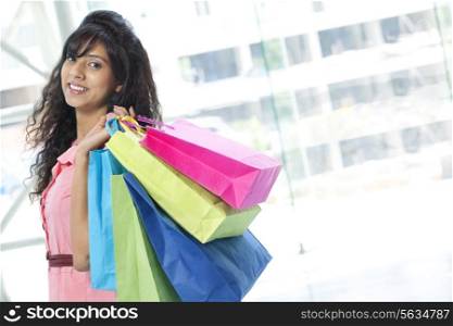 Portrait of pretty young woman smiling while carrying shopping bags