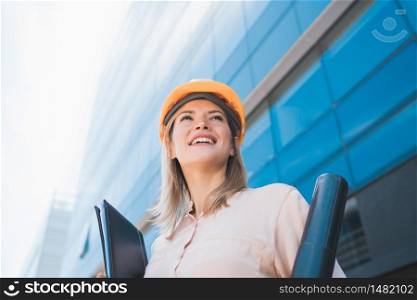 Portrait of professional architect woman wearing yellow helmet and standing outdoors. Engineer and architect concept.