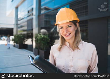 Portrait of professional architect woman wearing yellow helmet and standing outdoors. Engineer and architect concept.