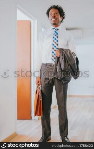 Portrait of professional businessman holding a briefcase while standing at modern office. Business concept.