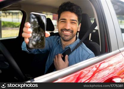 Portrait of professional male driver showing something on screen phone. Transport concept.