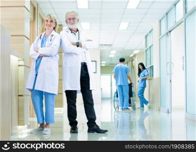 Portrait of professional senior doctors standing in hall of hospital with blur background of staff. Insurance, Service and Medical Concept.