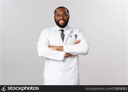 Portrait of proud and confident african-american male doctor in white coat, cross hands chest and smiling pleased, boastful over his nurses and best hospital in town, taking care of patients.. Portrait of proud and confident african-american male doctor in white coat, cross hands chest and smiling pleased, boastful over his nurses and best hospital in town, taking care of patients