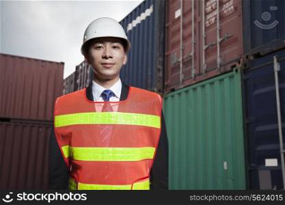 Portrait of proud engineer in protective workwear standing in a shipping yard