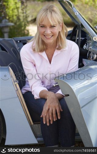 Portrait Of Proud Mature Woman Sitting In Restored Classic Sports Car Outdoors At Home                             