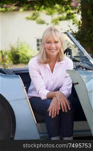 Portrait Of Proud Mature Woman Sitting In Restored Classic Sports Car Outdoors At Home
