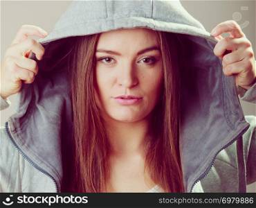 Portrait of rebellious pensive thoughtful teenager girl wearing sweatshirt with hood.
