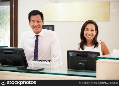 Portrait Of Reception Staff At Hotel Front Desk