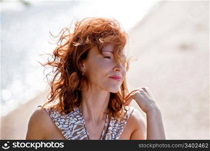 Portrait of red-haired adult women in dune at the sea