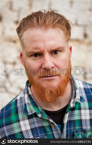 Portrait of red haired hipster man with blue plaid shirt expressing a emotion
