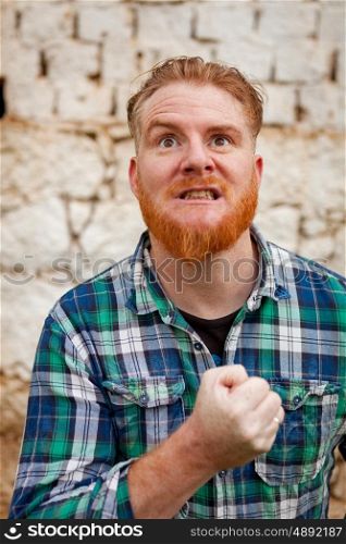 Portrait of red haired hipster man with blue plaid shirt expressing a emotion