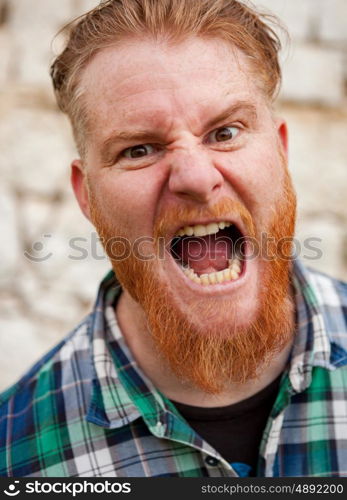 Portrait of red haired hipster man with blue plaid shirt expressing a emotion