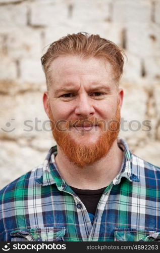 Portrait of red haired hipster man with blue plaid shirt looking at camera