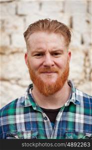 Portrait of red haired hipster man with blue plaid shirt looking at camera
