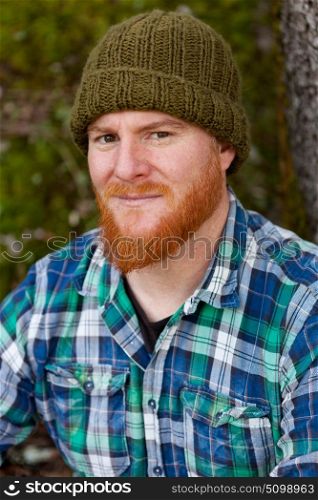 Portrait of red haired man with plaid shirt looking at camera