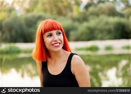 Portrait of red haired woman next to a lake enjoying of the nature