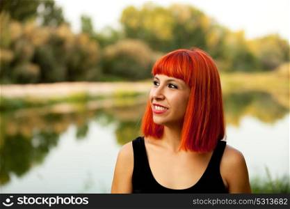 Portrait of red haired woman next to a lake enjoying of the nature