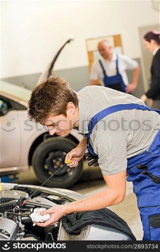 Portrait of repairman checking oil with dipstick