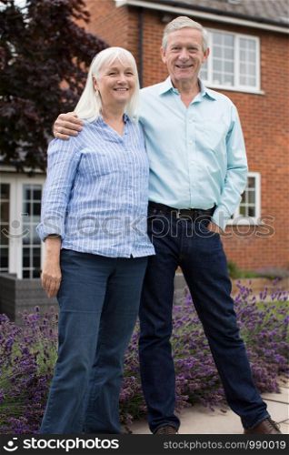 Portrait Of Retired Couple Standing Outside Home
