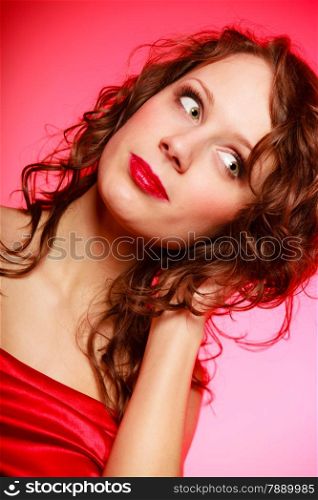 Portrait of romantic curly young woman girl in red dress on pink. Studio shot. Valentines Day.