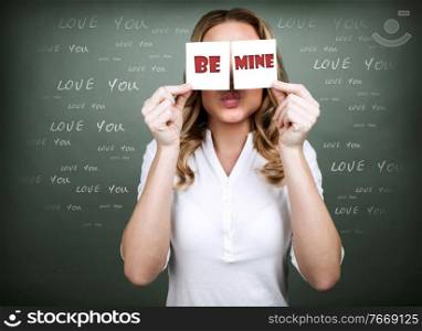 Portrait of romantic female with paper card with text  be mine , love you, conceptual photo of woman expresses affection, Valentines day