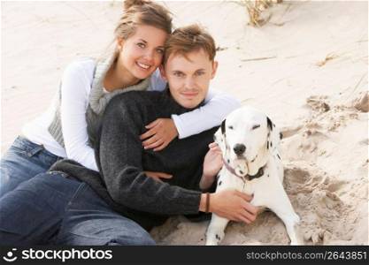 Portrait Of Romantic Teenage Couple On Beach With Dog