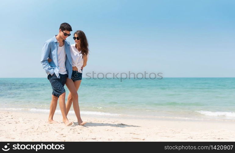 Portrait of Romantic Young couple in casual wear sun glasses walking at the beach with blue sky. Happy smiling Handsome man and Beautiful woman in love. Lover, dating, romance.