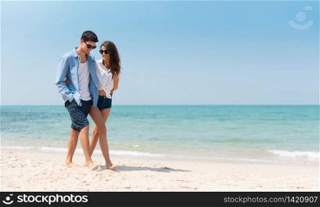 Portrait of Romantic Young couple in casual wear sun glasses walking at the beach with blue sky. Happy smiling Handsome man and Beautiful woman in love. Lover, dating, romance.