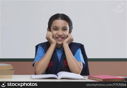 Portrait of rural girl in school uniform sitting at table