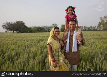 Portrait of rural Indian family with father carrying daughter on shoulders