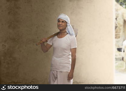 Portrait of rural old farmer carrying hoe on his shoulder