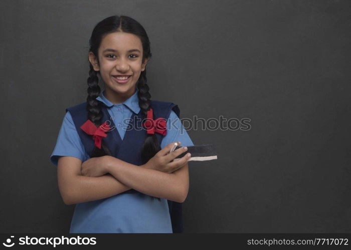 Portrait of rural school girl standing arms crossed in front of blackboard