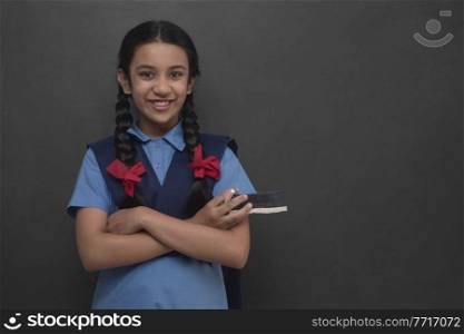 Portrait of rural school girl standing arms crossed in front of blackboard