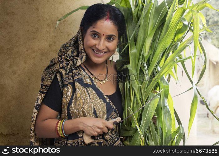 Portrait of rural woman holding bunch of crops and sickle