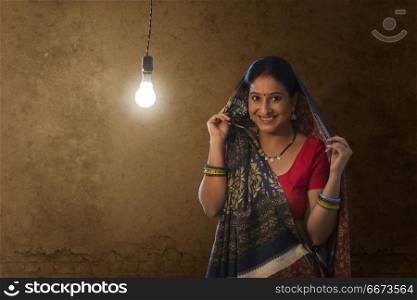 Portrait of rural woman standing against light bulb in house