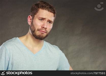 Portrait of sad depressed handsome man in shirt crying. Young guy posing in studio on black.
