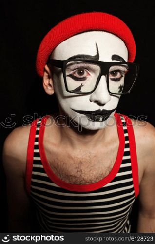 Portrait of sad mime wearing eyeglasses on black background