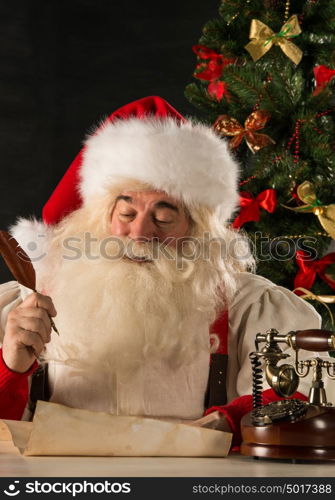 Portrait of Santa Claus answering Christmas letters using vintage tools - paper roll, feather pen, ink, wooden retro phone