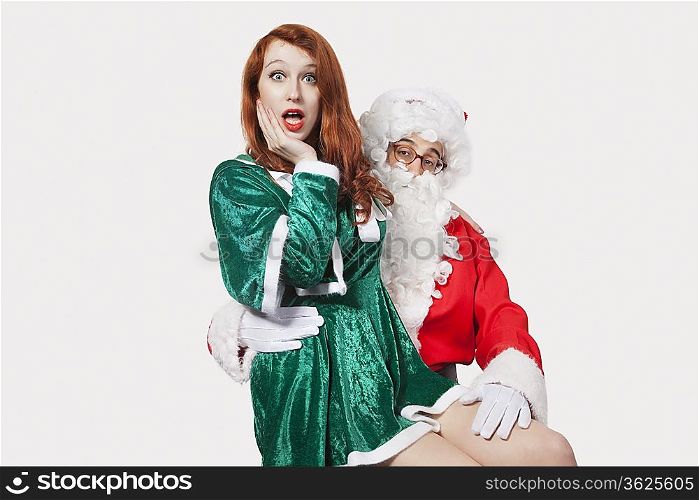 Portrait of Santa touching woman inappropriately against gray background