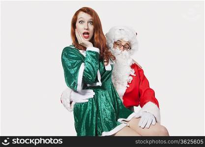 Portrait of Santa touching woman inappropriately against gray background
