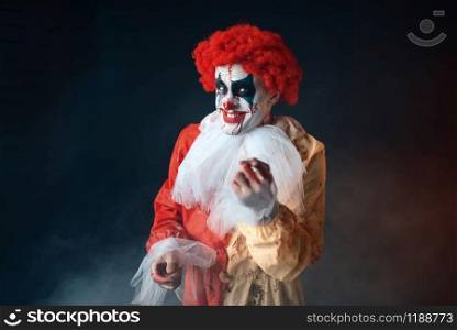 Portrait of scary bloody clown with crazy eyes. Man with makeup in carnival costume, mad maniac. Portrait of scary bloody clown with crazy eyes