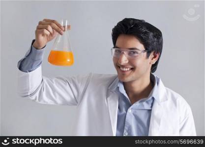 Portrait of scientist smiling and holding flask